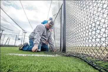  ?? NWA Democrat-Gazette/ANTHONY REYES • @NWATONYR ?? Chris Gibson (front) and James Selvey, both with Springdale’s Park and Recreation Department, install netting Monday for batting cages at the Tyson Sports Complex in Springdale. The netting is stored for the winter to protect it from severe winter...