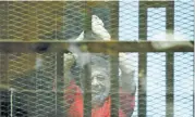  ?? (AFP) ?? This file photo shows Mohamed Morsi, wearing a red uniform, gesturing from behind the bars during his espionage trial on June 18, 2016