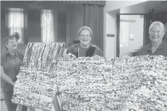  ??  ?? From left, Pennyann Styles, Vera Trimble and Miriam Woods display the mats they help weave from old milk bags. The mats are shipped to Africa and Haiti to serve as beds for children.