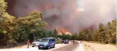  ?? Associated Press ?? ↑
Police officers and residents watch a raging wildfire in Antalya, Turkey, on Wednesday.