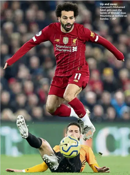  ??  ?? Up and away:
Liverpool’s Mohamed Salah gets past the tackle of Wolves’ Joao Moutinho at Anfield on Sunday. — AP