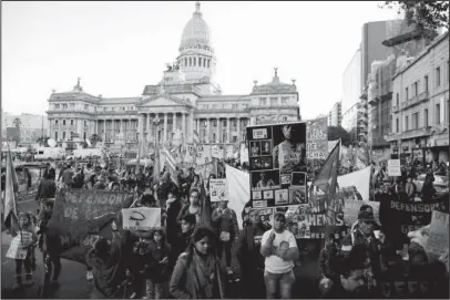  ?? The Associated Press ?? NOT ONE LESS: Maira Maidana, bottom right, holds a banner with pictures of herself during a June 3 march organized by the movement “Ni Una Menos,” or Not One Less, to protest violence against women in Buenos Aires, Argentina. “With Ni Una Menos, women...