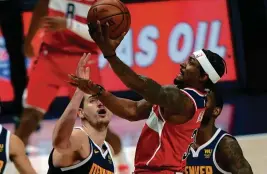  ?? JACK DEMPSEY/AP ?? Wizards guard Bradley Beal, center, goes up for a shot against Nuggets center Nikola Jokic, left, and forward Will Barton on Thursday in Denver. Beal finished with 33 points in the Wizards’ 112-110 victory.