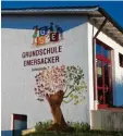  ?? Foto: Simone Kuchenbaur ?? An der Außenwand der Turnhalle hat Kirchenmal­er Peter Engelhardt ein großes Wandbild erstellt. Es zeigt das Logo der Schule sowie den Schulprofi­l Baum unter dem Motto „Gemeinsam stark werden“.