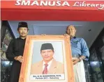  ??  ?? KENANG JASA: Kris Aji (kiri) dan Mujiono membawa foto almarhum Nasihuddin.