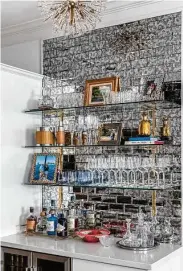  ?? ?? What used to be a small desk was reinvented as a bar with glass shelves on an antiqued mirror tiled wall.