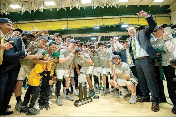  ?? Brian Jenkins/University of Vermont Athletics ?? The Vermont Catamounts celebrate with the America East Conference Tournament championsh­ip trophy after defeating Albany 56-53 to punch their ticket to the NCAA Tournament.