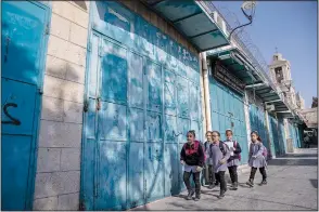  ?? ?? Palestinia­n children walk past closed souvenir shops Nov. 16 at the tourist market adjacent to the Church of the Nativity.