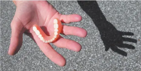  ?? AP FILE PHOTO ?? In this Aug. 26, 2014 photo, Gail Turner holds a partial set of dentures in Panama City, Fla. Turner’s nephew found them on a camp chair owhile cleaning the street following a downtown festival. Sometimes, missing dentures aren’t so easy to find.