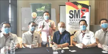  ??  ?? Riot (seated, centre) shows the ‘Teh C Special’ canned drink, produced by one of SME Sarawak’s member companies. The Serian MP is flanked by Raymond (second left) and Voon.