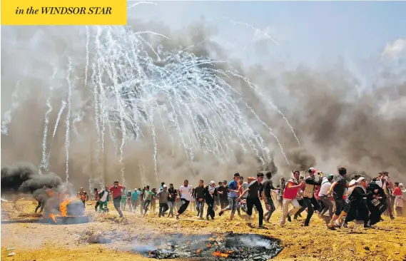  ?? MOHAMMED ABED / AFP / GETTY IMAGES ?? Palestinia­ns run from tear gas during clashes with Israeli troops near the Gaza-Israeli border Monday, as Palestinia­ns protest over the opening of the U.S. Embassy in Jerusalem.