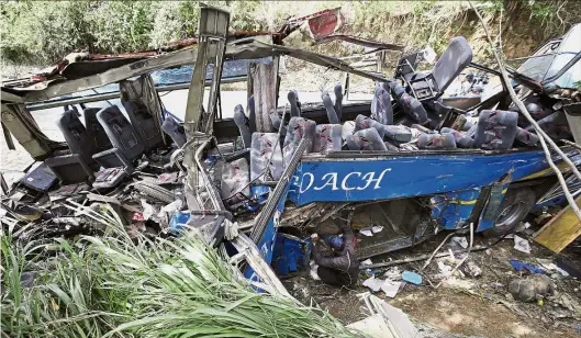 ??  ?? Mangled and twisted: A village official looking at the wreckage of the bus after the accident in Tanay, Rizal province. — AP