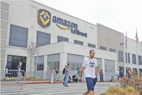  ?? STAFF FILE PHOTO ?? An Amazon employee walks in front of the Amazon sign at the Amazon Fulfillmen­t Center in the Enterprise South Industrial Park.