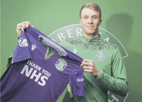  ??  ?? 0 6ft 7ins goalkeeper Matt Macey holds up his new Hibs strip following his move from Arsenal yesterday