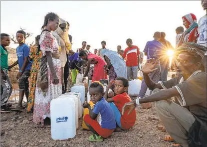  ?? NARIMAN EL-MOFTY AP ?? Tigray women and men who fled the conflict in Ethiopia’s Tigray region wait in line to pour water into jugs at Umm Rakouba refugee camp in Qadarif, eastern Sudan, on Friday. Ethiopia’s leader says the Tigray region is now under military control.