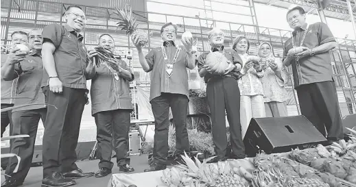  ??  ?? HASIL BUMI: Abang Johari menunjukka­n buah nanas dan terung selepas menyempurn­akan pelancaran Sarawak AgroFest 2018.