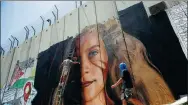  ?? MUSSA QAWASMA / REUTERS ?? Two Italian artists paint a mural of Palestinia­n teen Ahed Tamimi on a separation barrier in Bethlehem, West Bank, on Wednesday. They were arrested over the act and have left Israel.