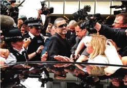  ??  ?? This file photo taken on August 24, 2010 shows British singer George Michael (center), leaving after appearing at Highbury Corner Magistrate­s Court in London.