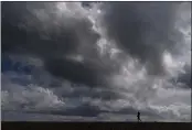  ?? JAE C. HONG — THE ASSOCIATED PRESS FILE ?? A woman strolls along the beach under rain clouds in Seal Beach.