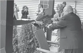  ?? KENT MALLETT/THE ADVOCATE ?? Tom Harvey, St. Vincent board treasurer, and Monsignor Paul Enke, right, pastor of St. Edward The Confessor Church in Granville, cut the ribbon Friday for the expansion of the St. Vincent Haven men’s shelter.