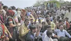  ?? — AP ?? PIPALYA, India: Protesters sit with the body of an Indian farmer killed Tuesday during a protest yesterday.