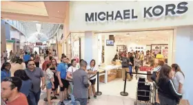  ?? ASSOCIATED PRESS ?? Shoppers line up outside a Michael Kors store in Miami. The luxury retailer said Wednesday that it would close 100 to 125 stores as its slump deepens.
