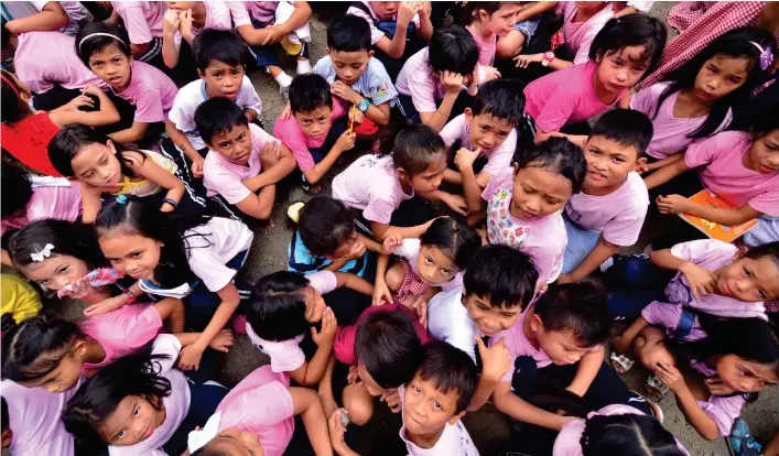  ?? MACKY LIM ?? FRIGHTENED. Students of Teodoro Palma Gil Elementary School duck at the open field after an earthquake struck Davao City around 10 a.m. yesterday. Just outside the school, a waiting shed collapsed leaving two persons injured.