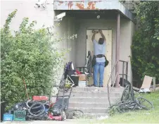  ??  ?? A worker boards up a doorway at the River Place apartments Wednesday.