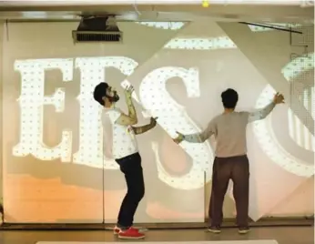  ??  ?? Artists in residence Paul Moleiro, left, and Romana Kassam adjust panels projecting the Honest Ed’s sign.