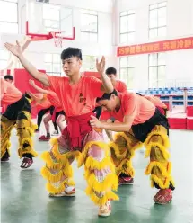  ??  ?? Qiu Haiwei (left) and Huang Qingliang practice a lion dance routine in the school gym.