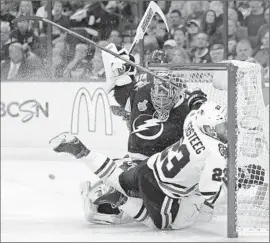  ?? Chris O’Meara Associated Press ?? CHICAGO RIGHT WING Kris Versteeg goes into the net as Tampa Bay goalie Ben Bishop tries to avoid the collision during the second period.