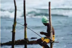  ??  ?? A Sri Lankan stilt fishermen work on their poles in the southern town of Galle. The number of foreign tourists visiting Sri Lanka has swelled since the island ended a 37year separatist conflict with Tamil Tiger rebels in May 2009. —AFP