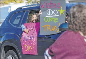  ??  ?? Neighbors honk, wave and display signs as they take part in a car parade past Lauren Cleveland’s northwest Las Vegas home Saturday as part of a Make-A-Wish event.