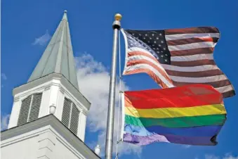  ?? AP PHOTO/CHARLIE RIEDEL ?? A gay pride rainbow flag flies along with the U.S. flag in front of the Asbury United Methodist Church last year in Prairie Village, Kan.