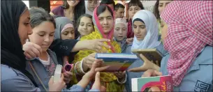  ??  ?? Malala Yousafzai, centre), distribute­s copies of her book to Syrian refugees at the opening of a school built by the Kayany Foundation NGO called the Malala Yousafzai All-Girls School in Barr Elias, Bekaa Valley.