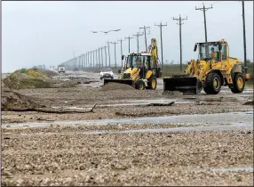  ?? AP/Houston Chronicle/MICHAEL CIAGLO ?? Crews work to clear sand and debris from a highway at Bolivar Peninsula, Texas, after Tropical Storm Cindy made landfall earlier Thursday.