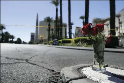  ?? AP PHOTO/MARCIO JOSE SANCHEZ ?? Flowers are placed near the scene of a mass shooting at a music festival near the Mandalay Bay resort and casino (top left) on the Las Vegas Strip, Monday.