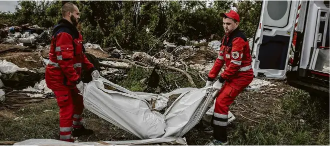  ?? Finbarr O’Reilly/The New York Times ?? Socorrista­s ucranianos removem corpo de soldado russo no vilarejo de Malaia Rohan, ao norte de Kharkiv