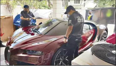  ?? ?? Bureau of Customs personnel inspect a red Bugatti Chiron 2023 model sports car recovered in a house in Ayala Alabang, Muntinlupa yesterday. Image courtesy of the BOC.