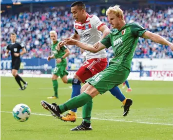  ??  ?? Martin Hinteregge­r trennt hier Bobby Wood vom Ball. Die Augsburger Defensive war gegen den HSV stabil. In der Offensive war man aber harmlos, erzielte kein Tor und verlor das sechste Saison Auftaktspi­el in Folge.