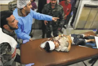  ?? George Ourfalian / AFP / Getty Images ?? Emergency workers at a hospital in Aleppo treat a child who was injured in a suicide car bombing directed at buses in the al-Rashideen area. No one claimed responsibi­lity for the attack.
