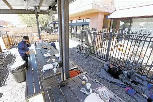  ?? LUIS SÁNCHEZ SATURNO/THE NEW MEXICAN ?? Claudio Martinez of Santa Fe, a guest at Pete’s Place, cleans new benches in front of the shelter Wednesday. The city has delayed renewing the shelter’s lease, saying the building needs a state fire and safety inspection.