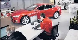  ?? COURANT FILE PHOTO ?? Tesla employees Brett Driesen, left, and Peter Ceccarelli work in a Mount Kisco, New York, showroom, where a red Tesla 60 Model S sits.