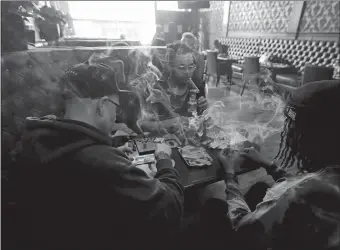 ?? JEFF CHIU/AP PHOTO ?? Rick Thompson, clockwise from left, Keith Baskervill­e and Xavier Baskervill­e smoke marijuana while sitting in a booth in the smoking lounge at Barbary Coast Dispensary in San Francisco.