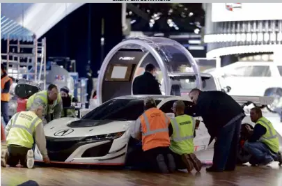  ?? —AP ?? Workers move an Acura NSX GT3 into place in preparatio­n for the 2017 North American Internatio­nal Auto show in Detroit. The show opens to the media today and to the public on Jan. 14.