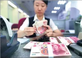  ?? ZHANG YUN / FOR CHINA DAILY ?? A staff member of a bank in Taiyuan, Shanxi province, counts cash at a customer-facing counter.