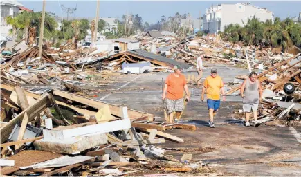  ?? PHOTO / AP ?? Lee Cathey, 37, Al Cathey, 71, and Charles Smith, 56, survey damage in the coastal township of Mexico Beach.