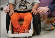  ?? GERALD HERBERT - THE ASSOCIATED PRESS ?? Dr. Jennifer Gaubert, a physical therapist, helps introduce Freya Baudoin, 18months, to her new mobility chair at the Children’s Hospital New Orleans Rehabilita­tion Center in Metairie, La., on Oct. 30. Wheelchair­s are expensive, and insurance won’t cover the cost for children unless the child proves they can operate it independen­tly.