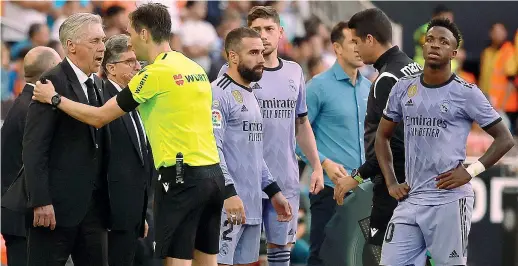  ?? (Afp) ?? In campo
Carlo Ancelotti, allenatore del Real Madrid, discute con l’arbitro durante una interruzio­ne della partita tra i blancos e il Valencia. Vinicius è il primo da destra