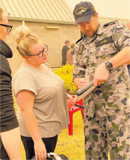  ?? Photo / AP ?? The names of Mallacoota evacuees are checked off before being ferried to the HMAS Choules offshore.